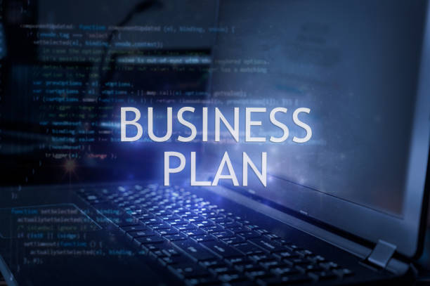 Business plan inscription against laptop and code background.